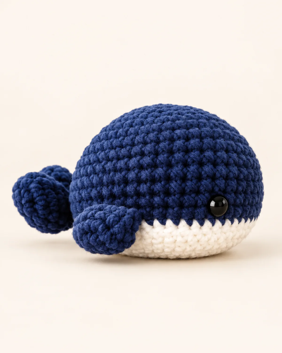 Navy Blue Whale Amigurumi, finished product on a warm off-white background